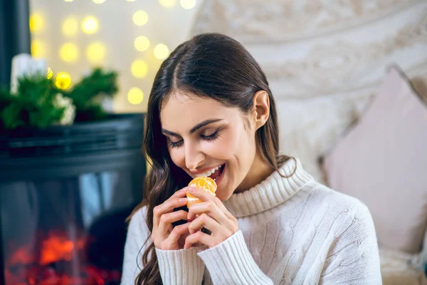 Mujer vestida de blanco comiendo una mandarina — Foto de Stock