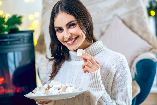 Жінка в білому одязі їсть зефір і посміхається — стокове фото