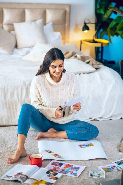 Schattige jonge vrouw knippen pistures van tijdschriften en het maken van een wishlist — Stockfoto