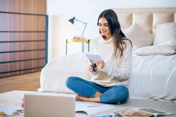 Mörkhårig ung kvinna skär pistures från tidningar och gör en önskelista — Stockfoto