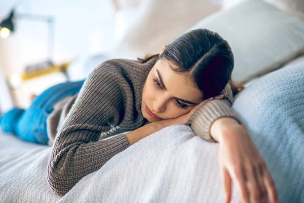 Mörkhårig kvinna liggande på sängen och ser deprimerad ut — Stockfoto