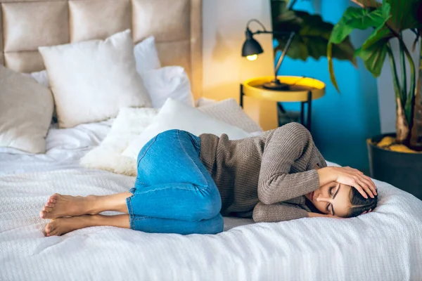 Wanita berambut gelap berbaring di tempat tidur dan tampak frustrasi — Stok Foto