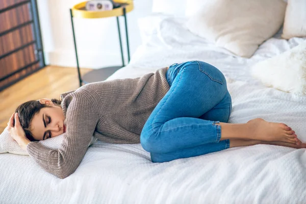 Wanita muda berambut gelap berbaring di tempat tidur dan merasa tertekan — Stok Foto