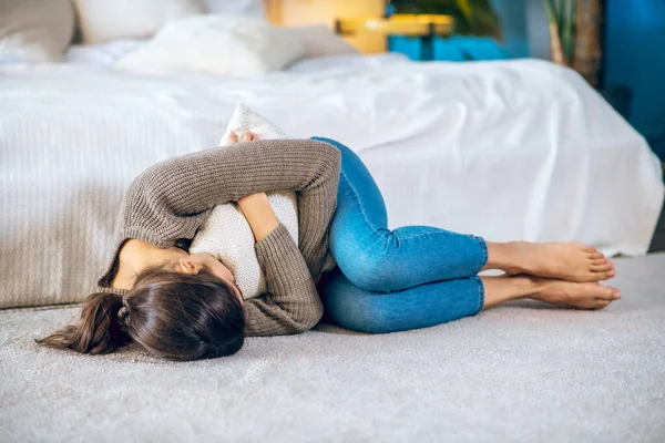 Молода жінка обіймає подушку і виглядає нещасною — стокове фото