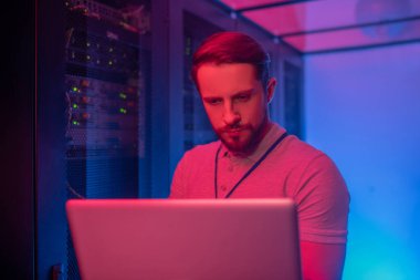 Sunucunun yanında duran laptoplu adam