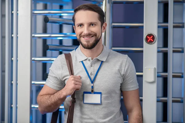 Hombre sonriente con placa y bolsa cerca del puesto de control — Foto de Stock