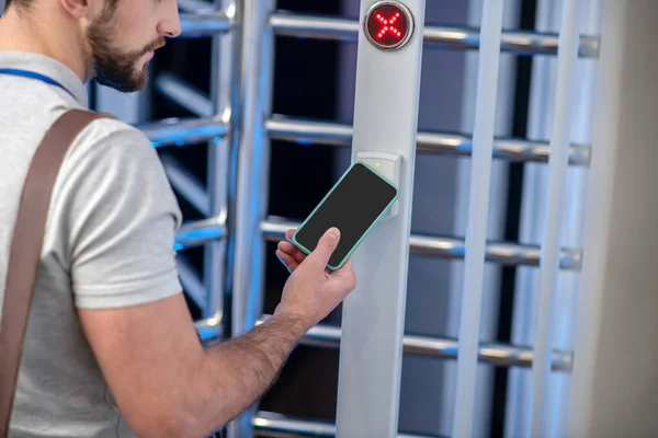Man applying smartphone to scanner at checkpoint — Stock Photo, Image