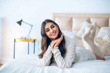 Koyu renk saçlı güzel bir kadın evinde dinleniyor.