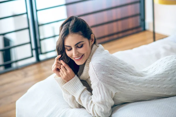 Mujer joven de cabello oscuro en ropa blanca buscando relajado y contento — Foto de Stock