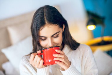 Elinde kırmızı bardakla güzel bir genç kadın.