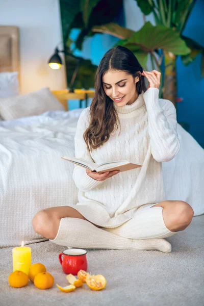 Jonge mooie vrouw zitten op de vloer en het lezen van een boek — Stockfoto