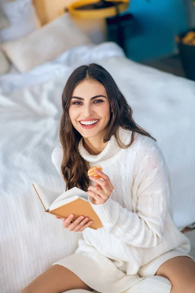 Mujer bonita sonriente sentada en el suelo y leyendo un libro — Foto de Stock