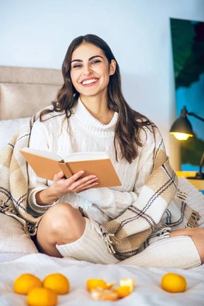 Giovane bella donna seduta con un libro nella sua camera da letto — Foto Stock