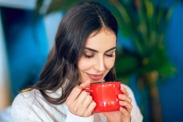 Mujer guapa de pelo oscuro con una taza roja en las manos — Foto de Stock