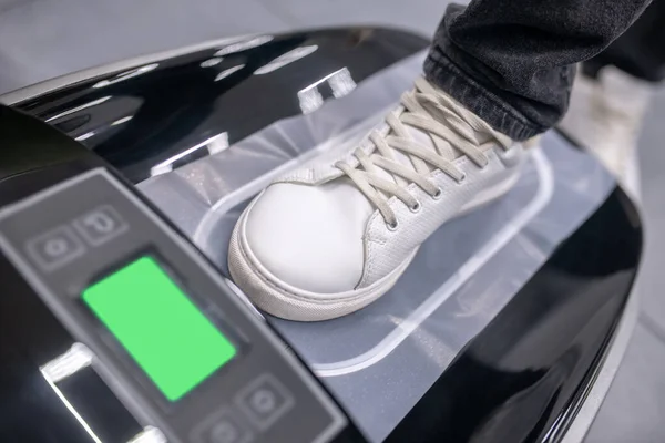 Foot in sneaker on electronic device with thermal film — Stock Photo, Image