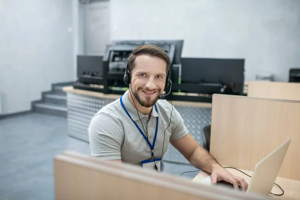 Усміхнений фахівець в навушниках позаду ноутбука — стокове фото