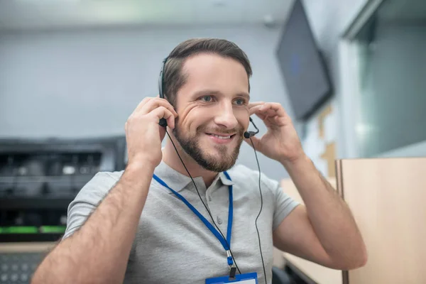 Hombre poniéndose auriculares mientras está sentado en el lugar de trabajo — Foto de Stock