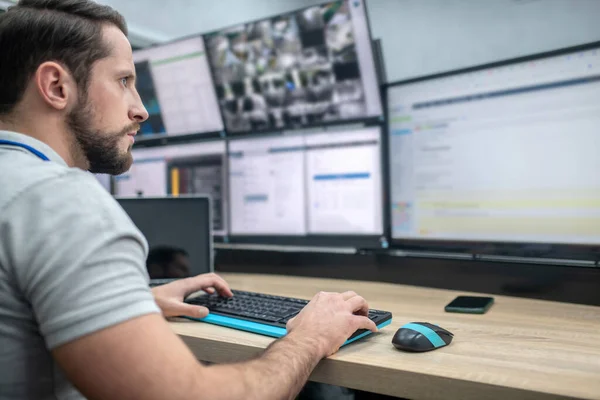 Hombre atento con teclado delante de las pantallas del ordenador — Foto de Stock