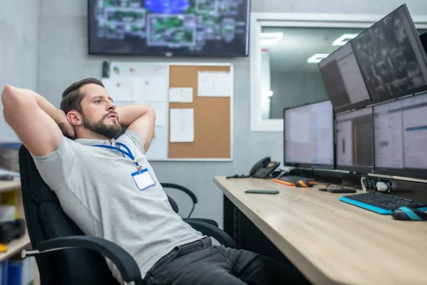 Trött man tittar på monitorer på jobbet — Stockfoto