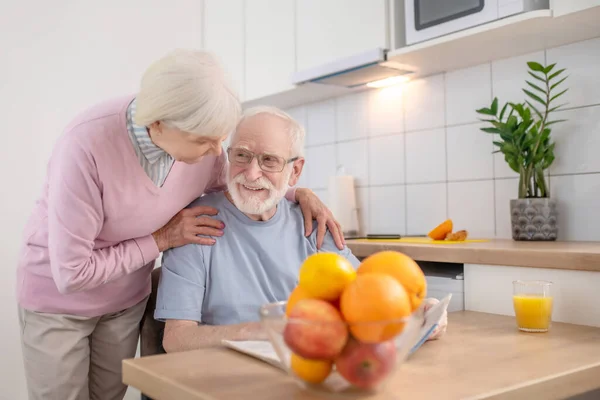 Mujer de pelo gris envejecida sirviendo una mesa para el desayuno de su marido — Foto de Stock