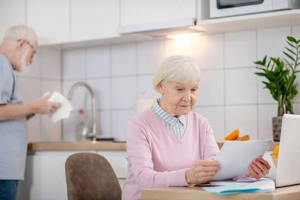 Grey-haired senior woman reading something and looking serious — Stock Photo, Image