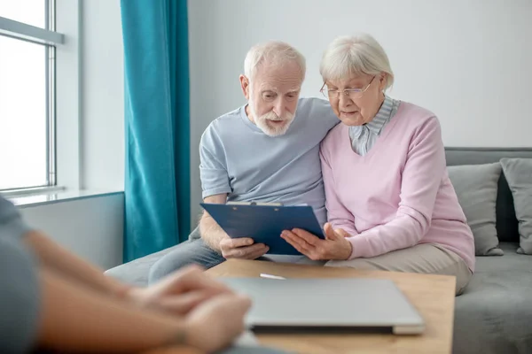 Couple âgé parlant à un agent de la compagnie d'assurance et regardant impliqué — Photo
