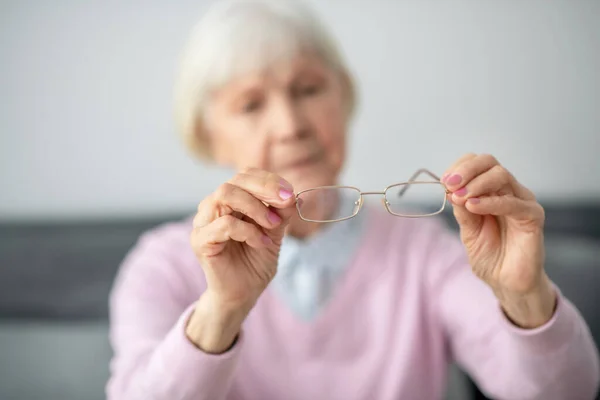 Senior woman holding eyeglasses in her hands — Stock Photo, Image