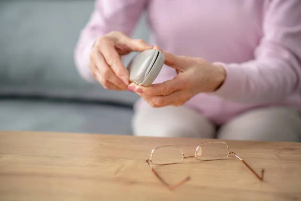 Seniorin mit Brille in der Hand — Stockfoto