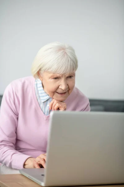 Senior kvinna sitter framför laptop och ser involverad — Stockfoto