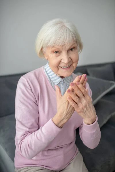 Anziani signora dai capelli grigi mostrando le mani e sorridendo — Foto Stock