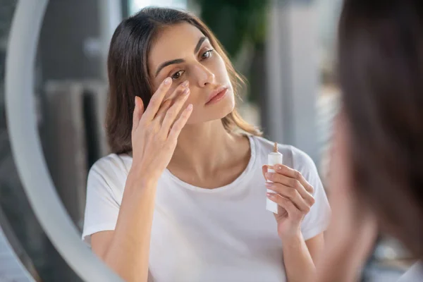 Mujer pegando un corrector a su piel — Foto de Stock