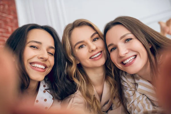 Три девушки делают селфи и выглядят счастливыми — стоковое фото