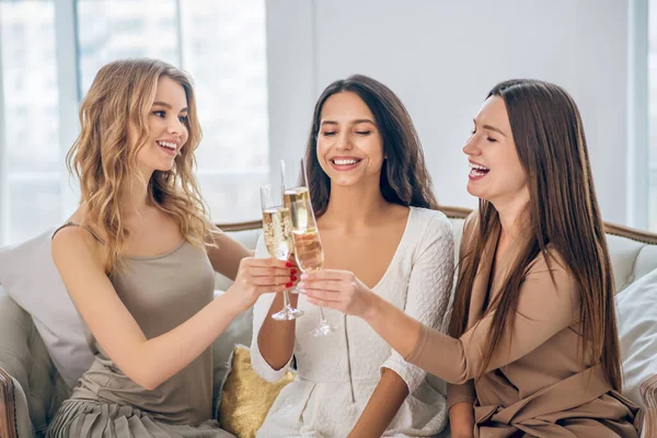 Three young girls having a party and drinking champagne — Stock Photo, Image