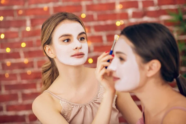 Menina loira aplicando máscara facial em seu rosto amigos — Fotografia de Stock
