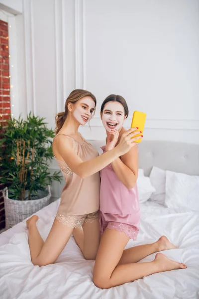 Deux jolies filles avec des masques faciaux faisant selfie — Photo