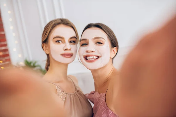 Pretty young girls with facial masks making selfie — Stock Photo, Image