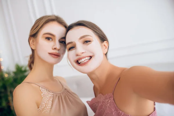 Guapas chicas jóvenes con máscaras faciales haciendo selfie —  Fotos de Stock