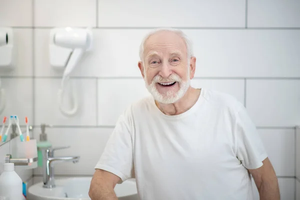 Hombre de pelo gris en camiseta blanca riendo vigorosamente — Foto de Stock