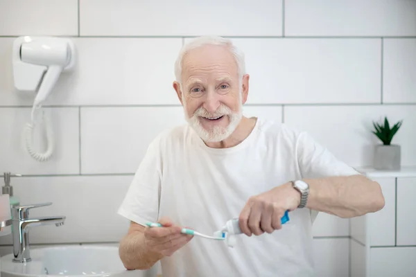 Hombre de camiseta blanca haciendo procedimientos matutinos en un baño — Foto de Stock