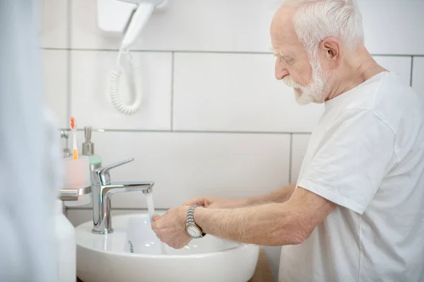Сіро-волохатий чоловік у білій сорочці миється у ванній — стокове фото