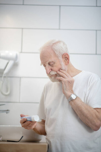 Седовласый мужчина в белой футболке со сливками и заботливо выглядящий