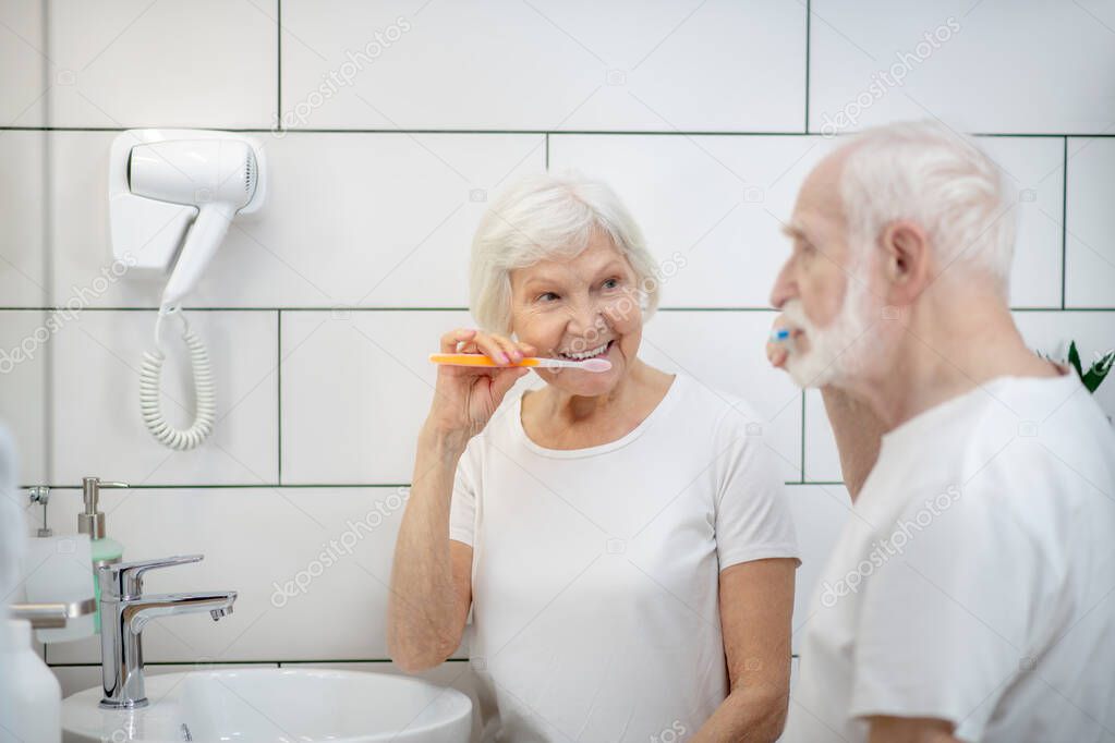 Elderly couple brushing their teeth together and feeling good