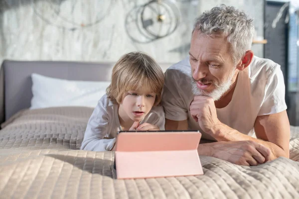 Kind met vader op zoek naar geïnteresseerde tablet — Stockfoto