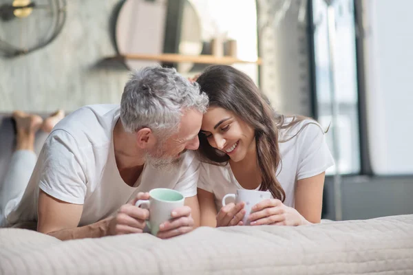 Man och kvinna med koppar som vidrör deras huvuden — Stockfoto