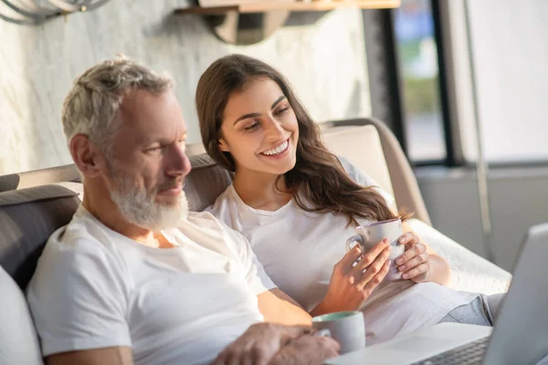 Engagerad man och kvinna med kaffe söker laptop — Stockfoto