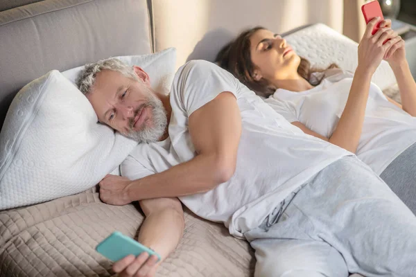 Kvinna och vände bort man ligger med smartphones — Stockfoto