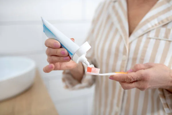 Close up foto van een vrouw knijpen tandpasta en een tandenborstel — Stockfoto