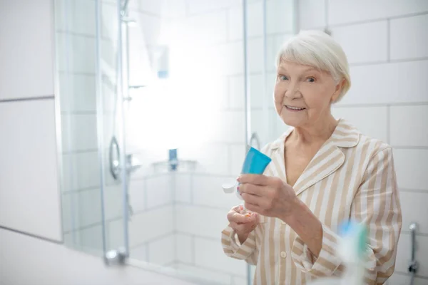 Oudere vrouw doet ochtendprocedures in de badkamer — Stockfoto