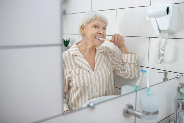 Banyoda dişlerini fırçalayan yaşlı kadın. — Stok fotoğraf