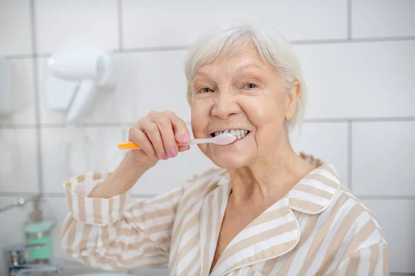 Äldre kvinna i pyjamas som rengör tänderna — Stockfoto